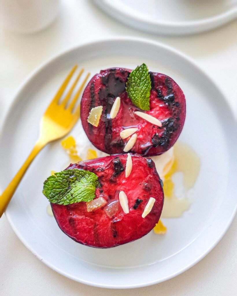 Grilled plums with candied ginger and whip cream on a plate